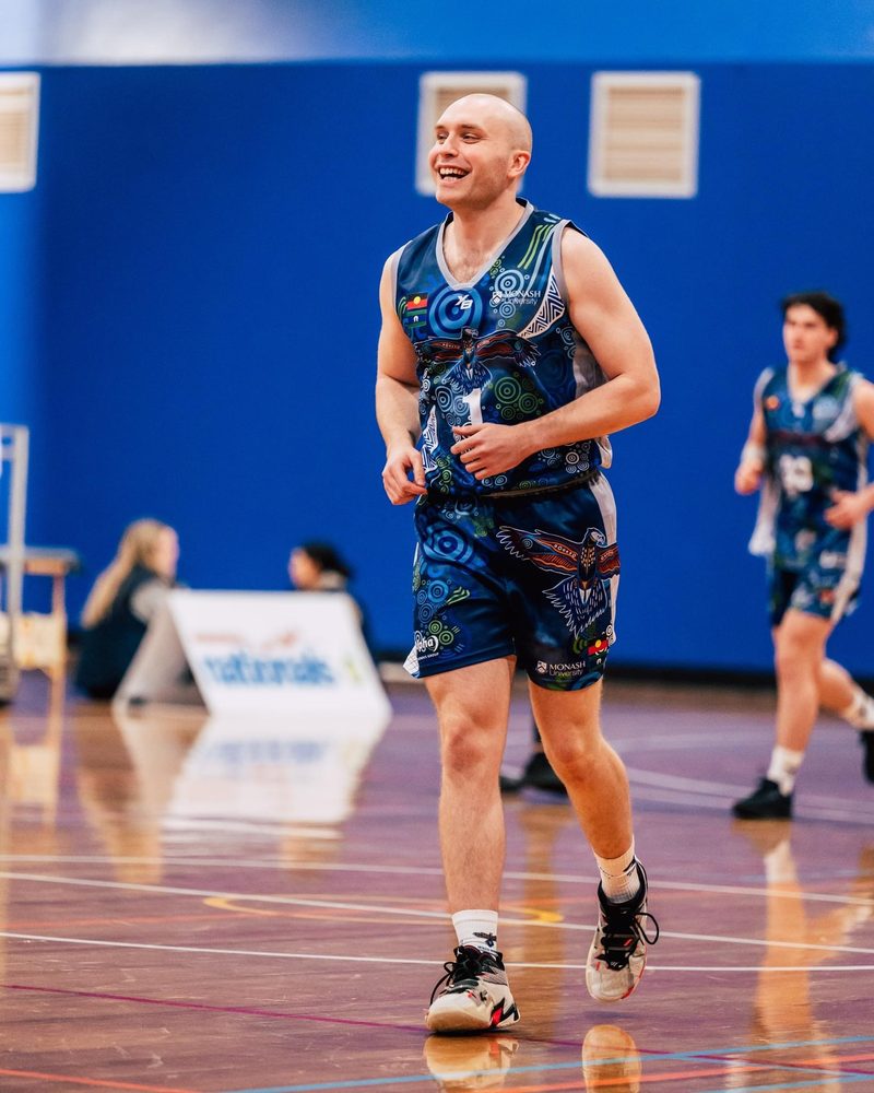 Cameron playing basketball, smiling as he runs back up the court