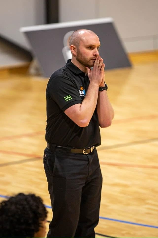 Cameron courtside during a game, hands clasped, watching his team